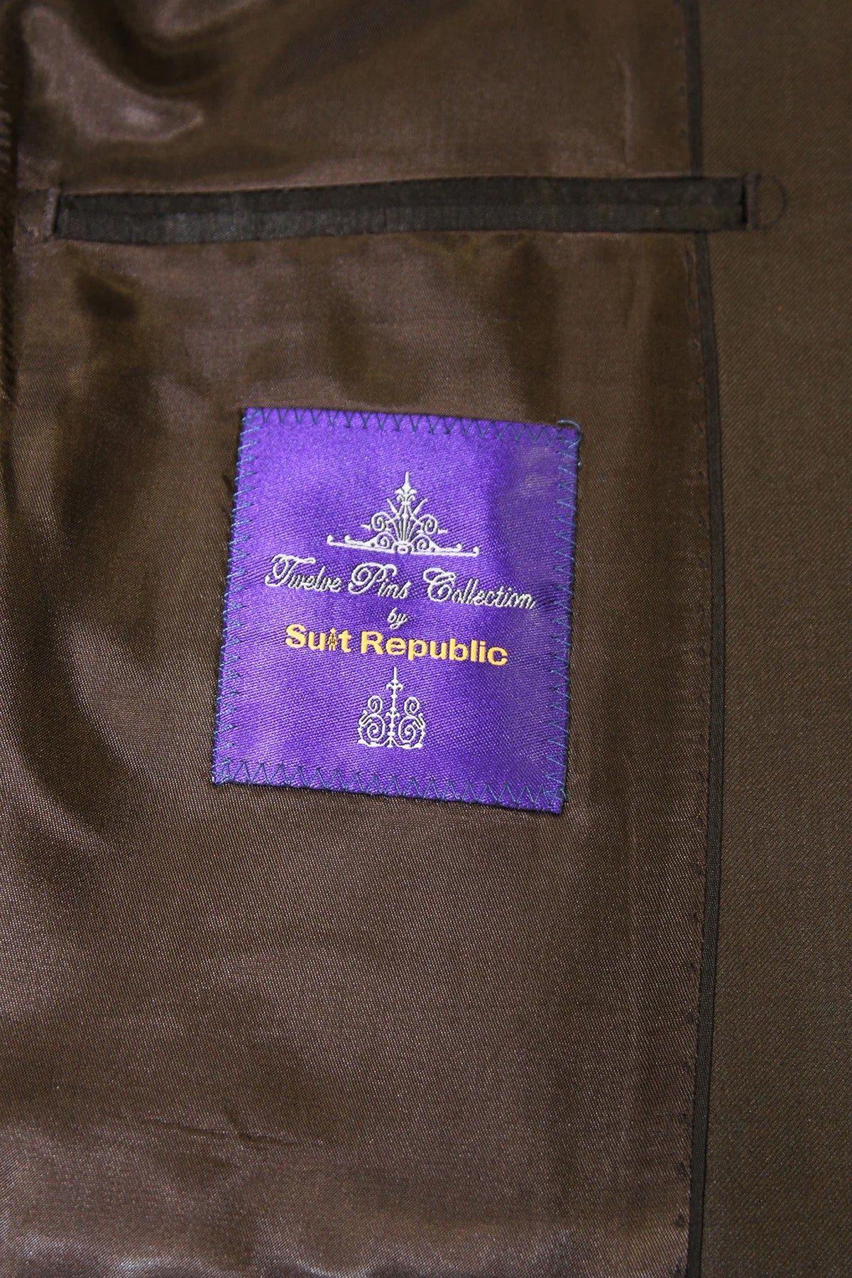 Close-up of a brown satin-like garment interior with a purple sewn label reading 'Tulip Par Collection by Suit Republic'.
